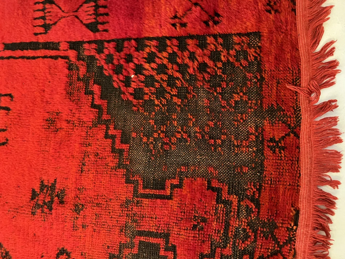 tappeto antico rosso e nero con motivi intricati in un ambiente accogliente.