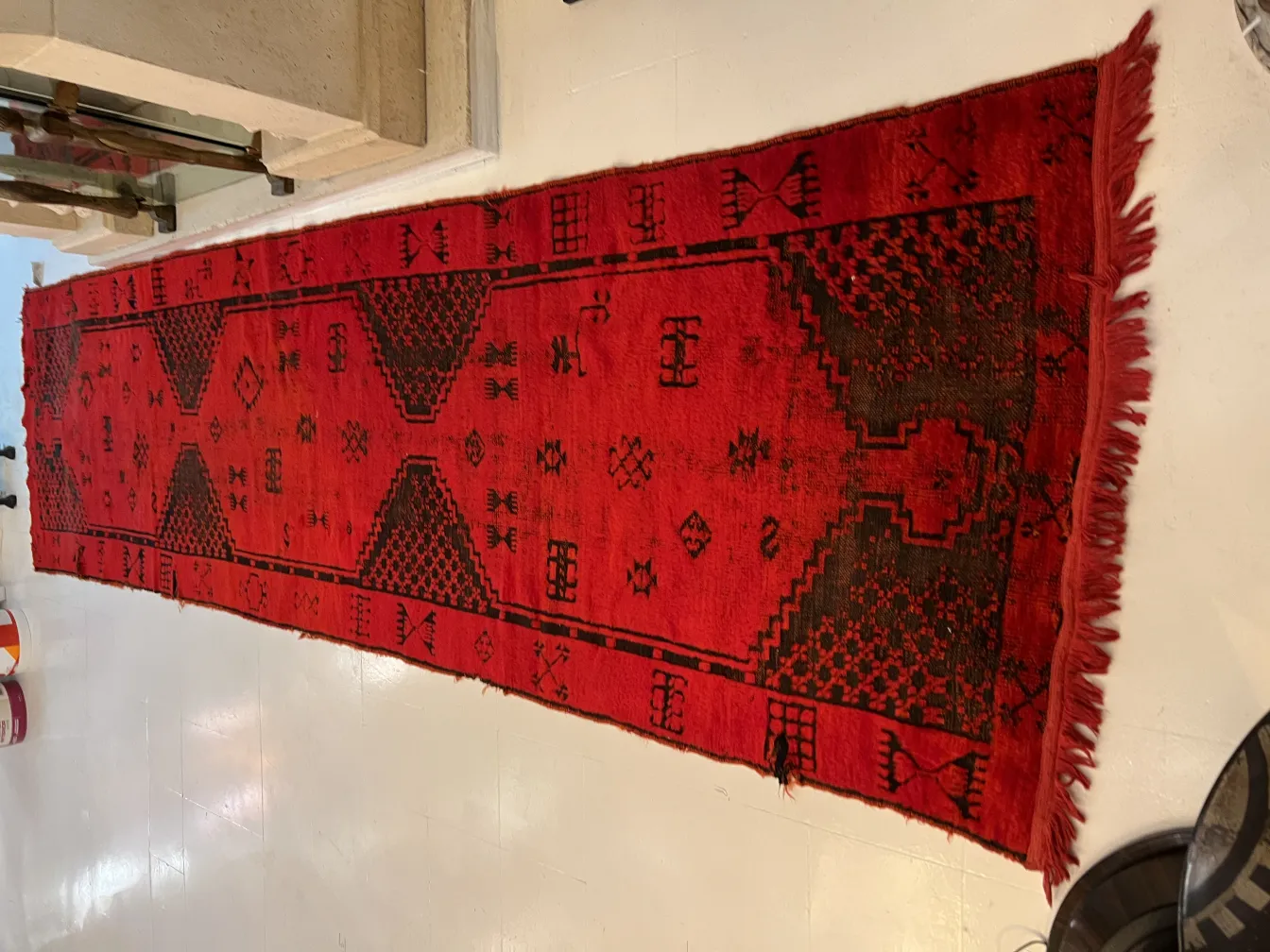 tapis ancien rouge avec des motifs géométriques et un fond clair
