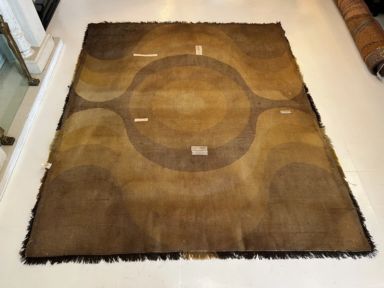 Alfombra antigua con patrones circulares en tonos marrones.