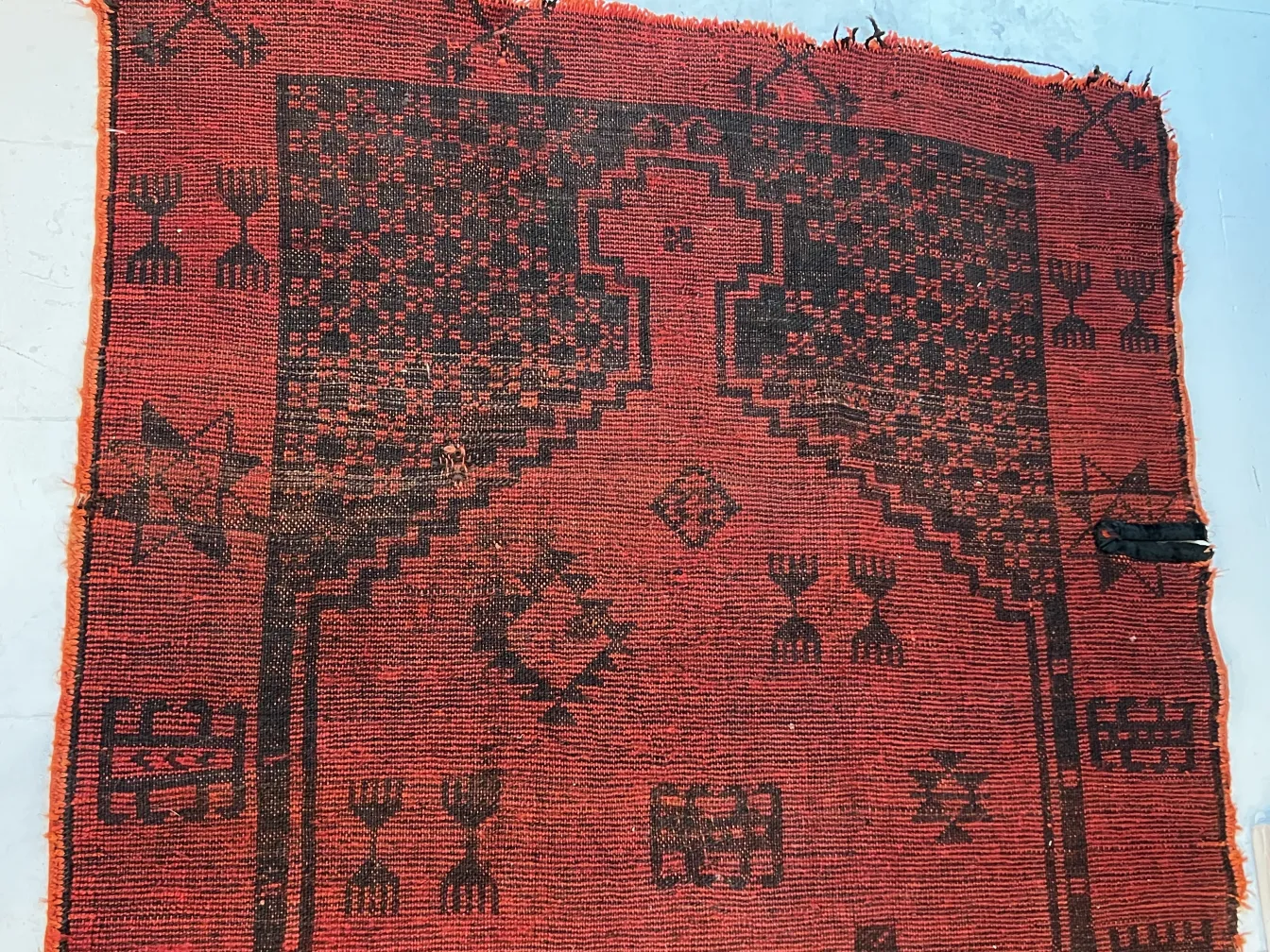 tapis antique rouge et noir avec des motifs géométriques
