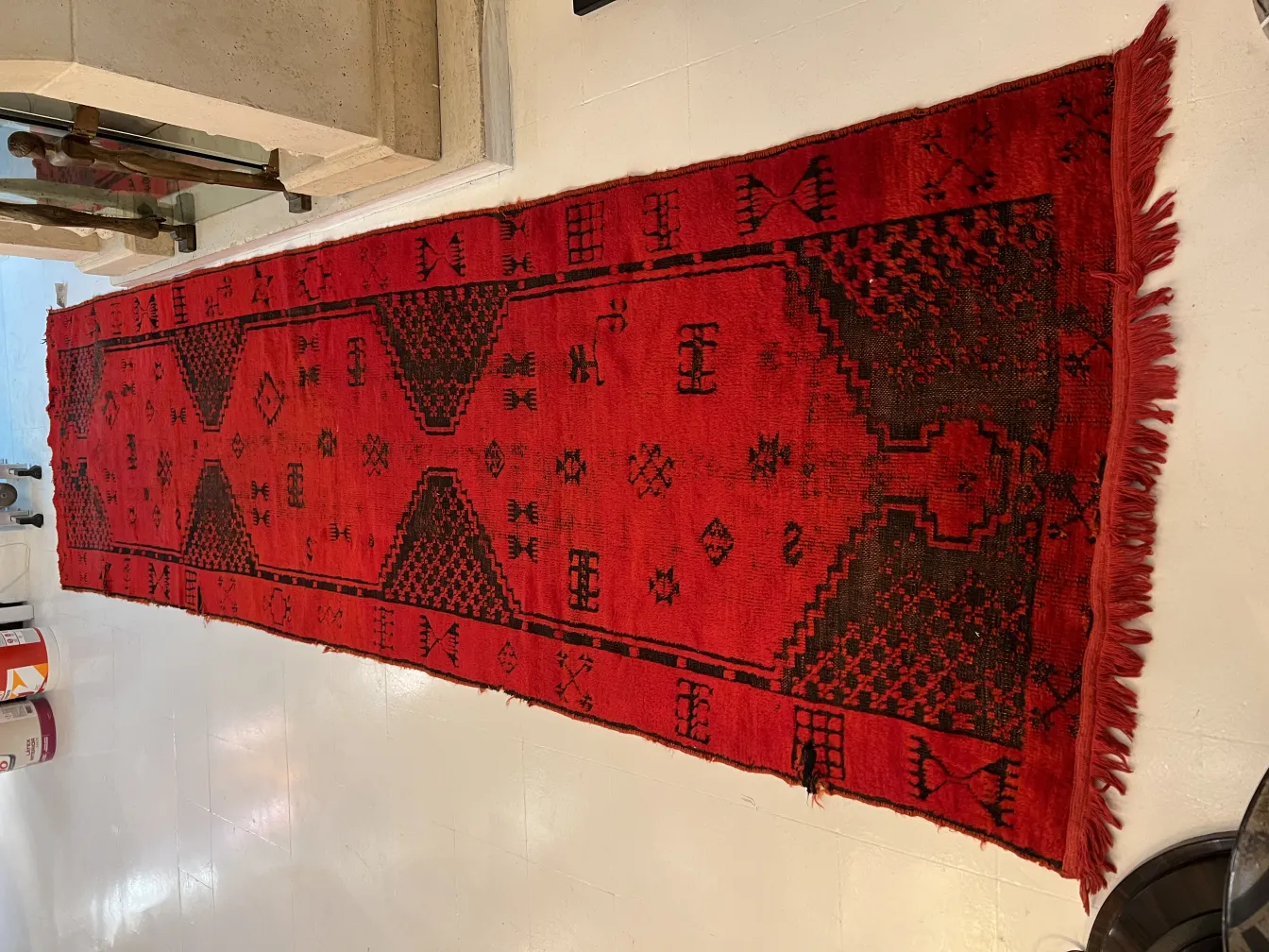 alfombra antigua roja con patrones geométricos en un entorno moderno