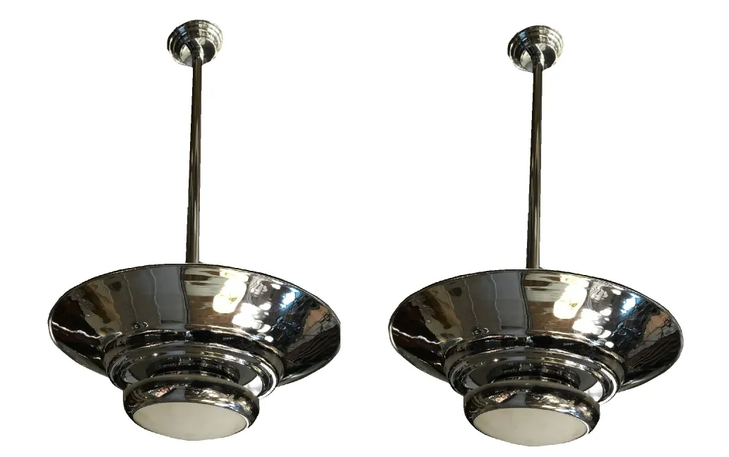 deux lustres anciens avec un design métallique brillant et des coupoles larges, illuminant un espace