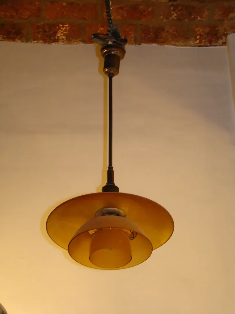 deux lustres anciens avec un design unique de Poul Henningsen, illuminant un espace chaleureux