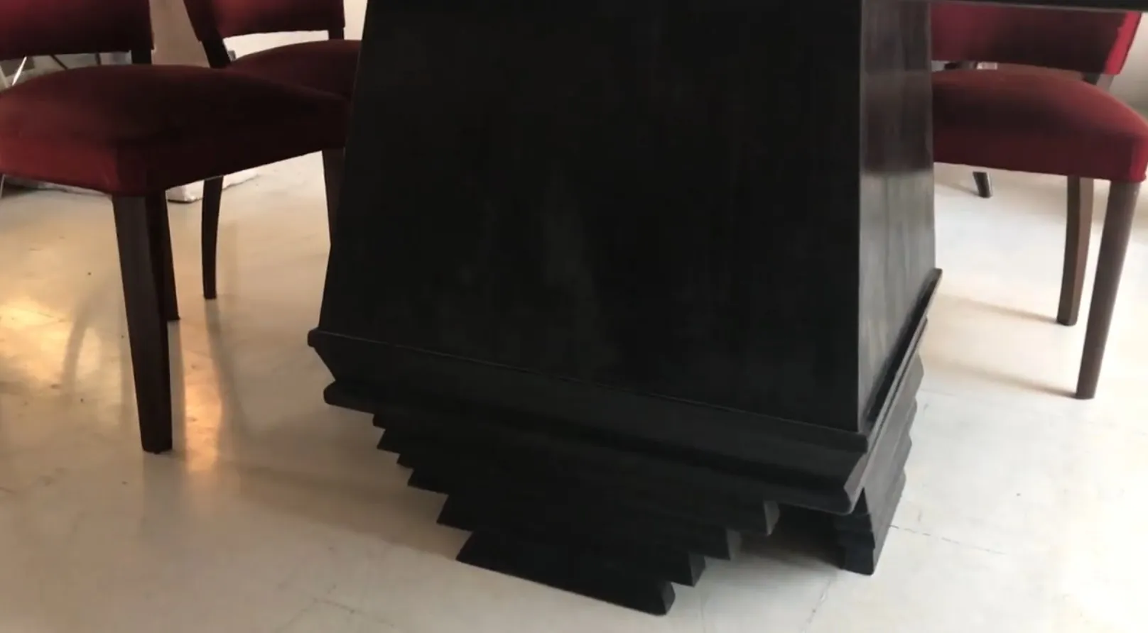 Mesa de comedor antigua con diseño art deco para 8 personas, rodeada de sillas rojas en un ambiente cálido.