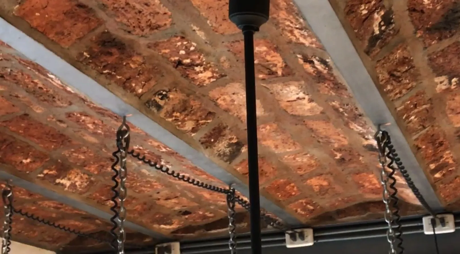 2 lampade a sospensione antiche appese a un soffitto in mattoni