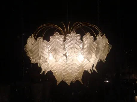 Ancien lustre avec feuilles en verre diffusant une lumière chaude