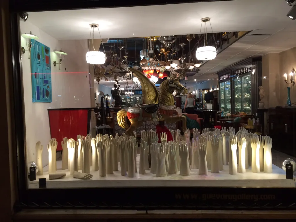 Two antique hanging lamps illuminating a showcase with artistic items.