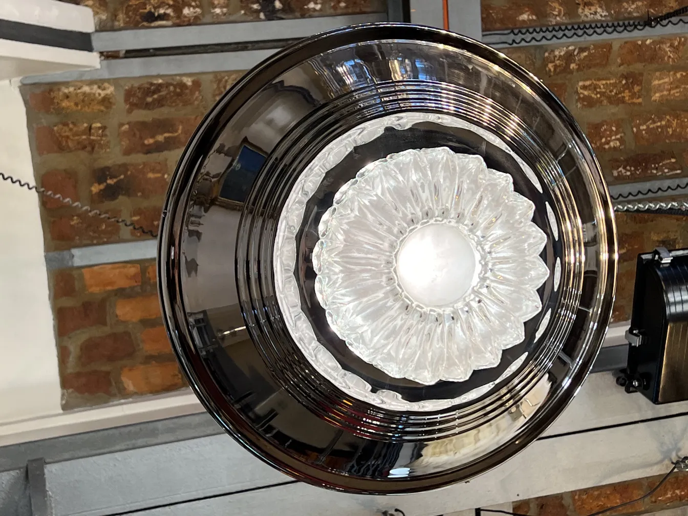 Две антикварные подвесные лампы с блестящей отделкой, подвешенные к держателю в рустикальной обстановке.