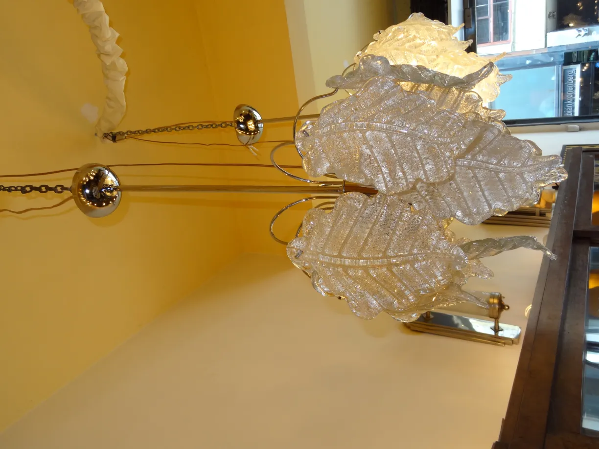 Two antique hanging lamps with shiny leaf design in a yellow room.