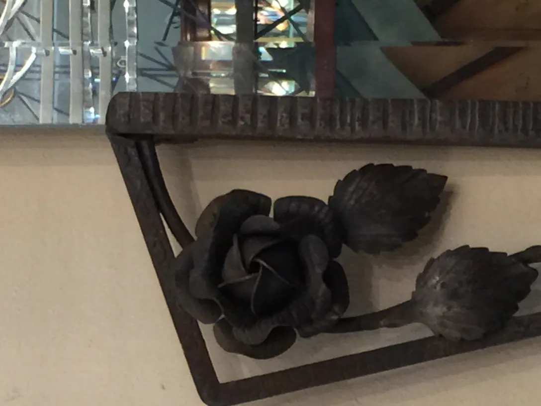 Antikes Spiegel mit Blumendekorationen am Boden.