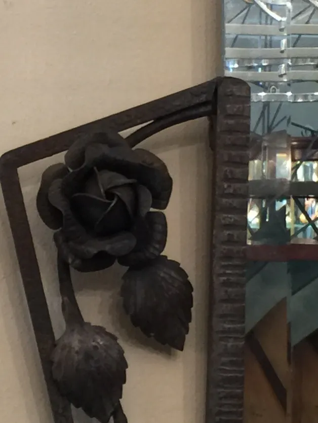 Antique mirror with a rose and leaf decorative design.