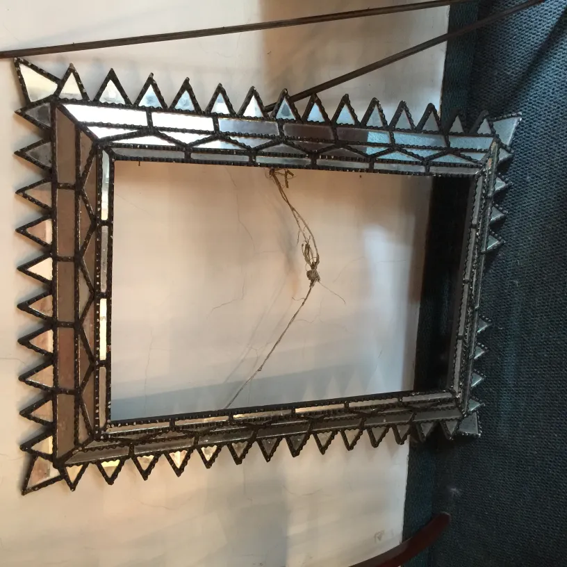 miroir ancien avec fond clair et cadre décoratif en forme de triangles