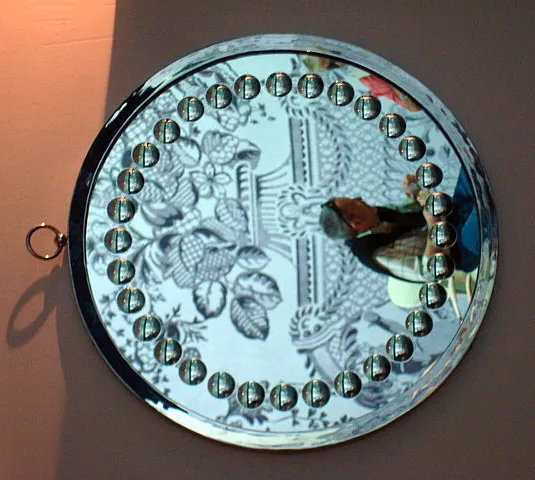 antique round mirror with decorative bevels, features clear details on its surface.