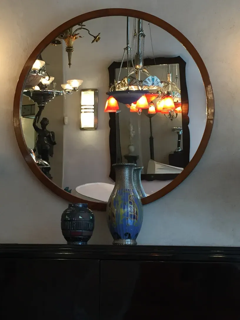 specchio antico rotondo con decorazioni visibili e riflessi in un ambiente elegante.