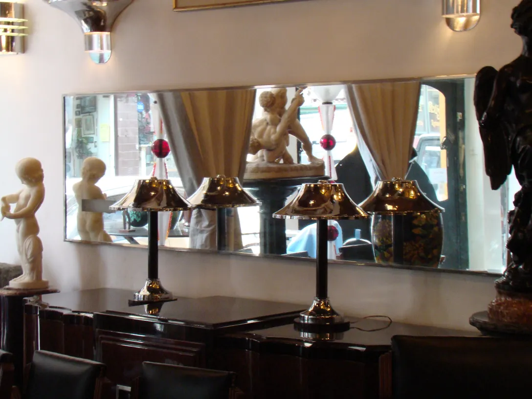 Specchio antico con lampade e statuette sullo sfondo.