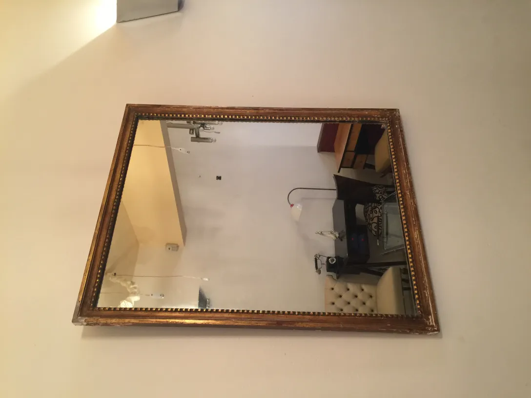 antique mirror in gilded frame hung on the wall