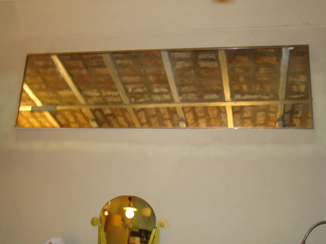 Espejo antiguo de pared con marco dorado, reflejando un techo.