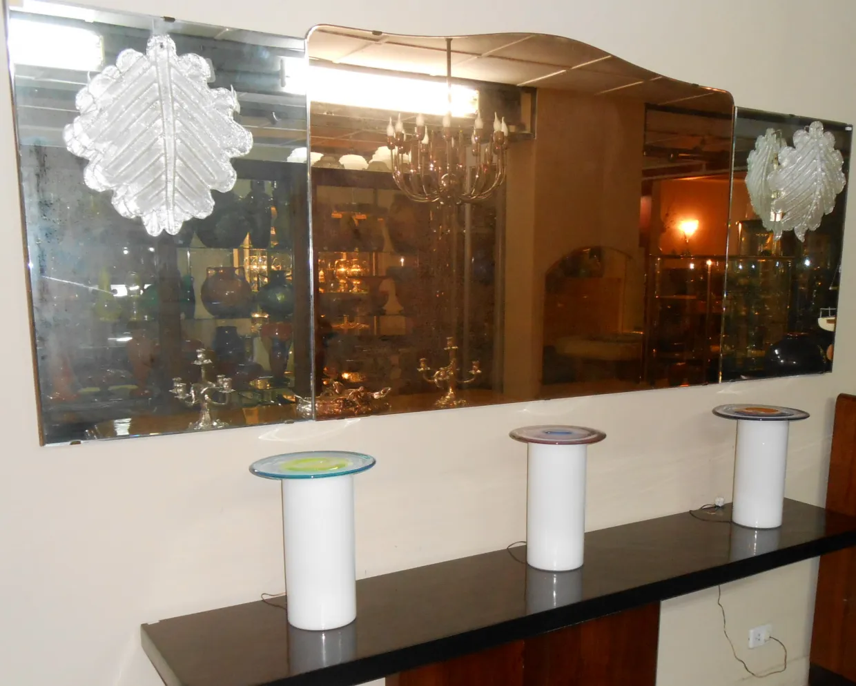 Antikes Spiegel mit Blattmuster, das die Umgebung reflektiert. Drei weiße Säulen herum.