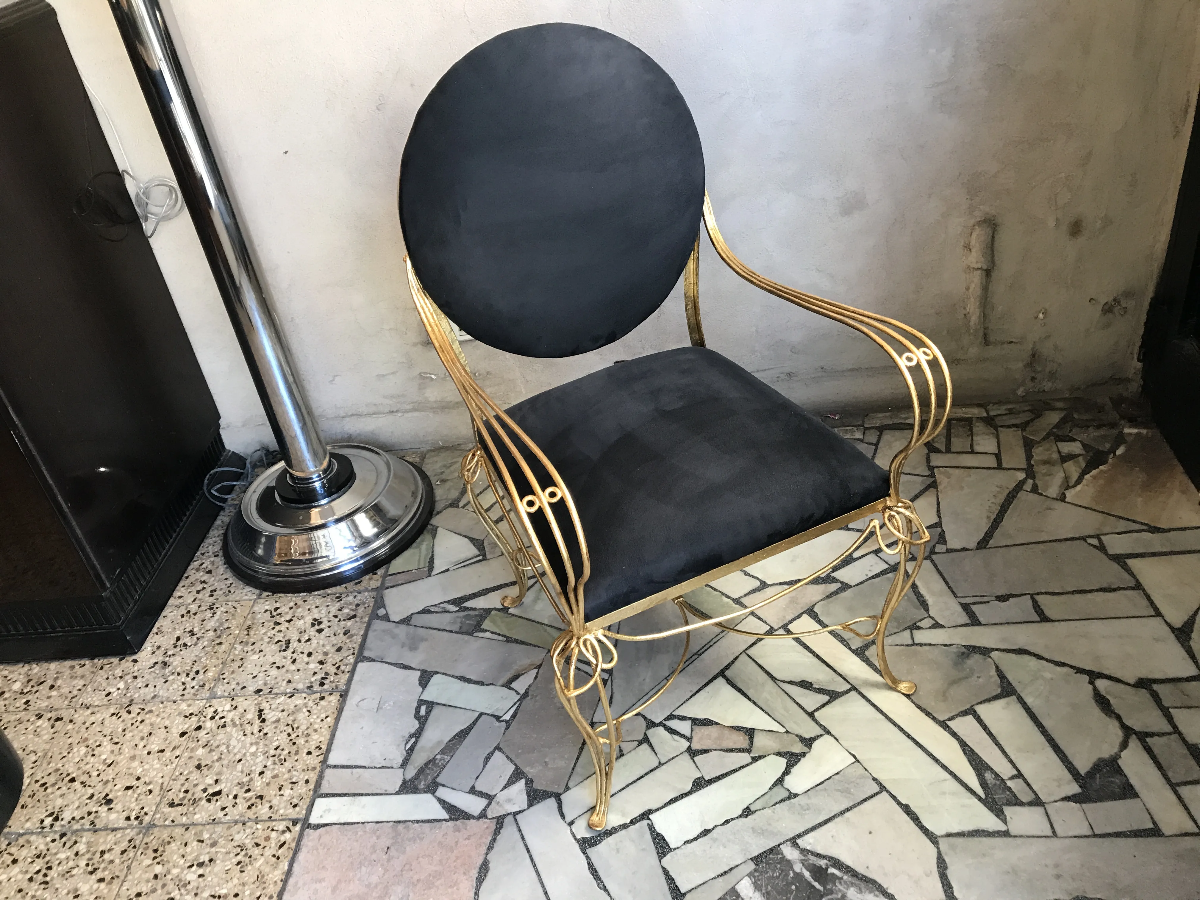 mesa de comedor antigüa de diseño redondo, con patas doradas y asiento negro