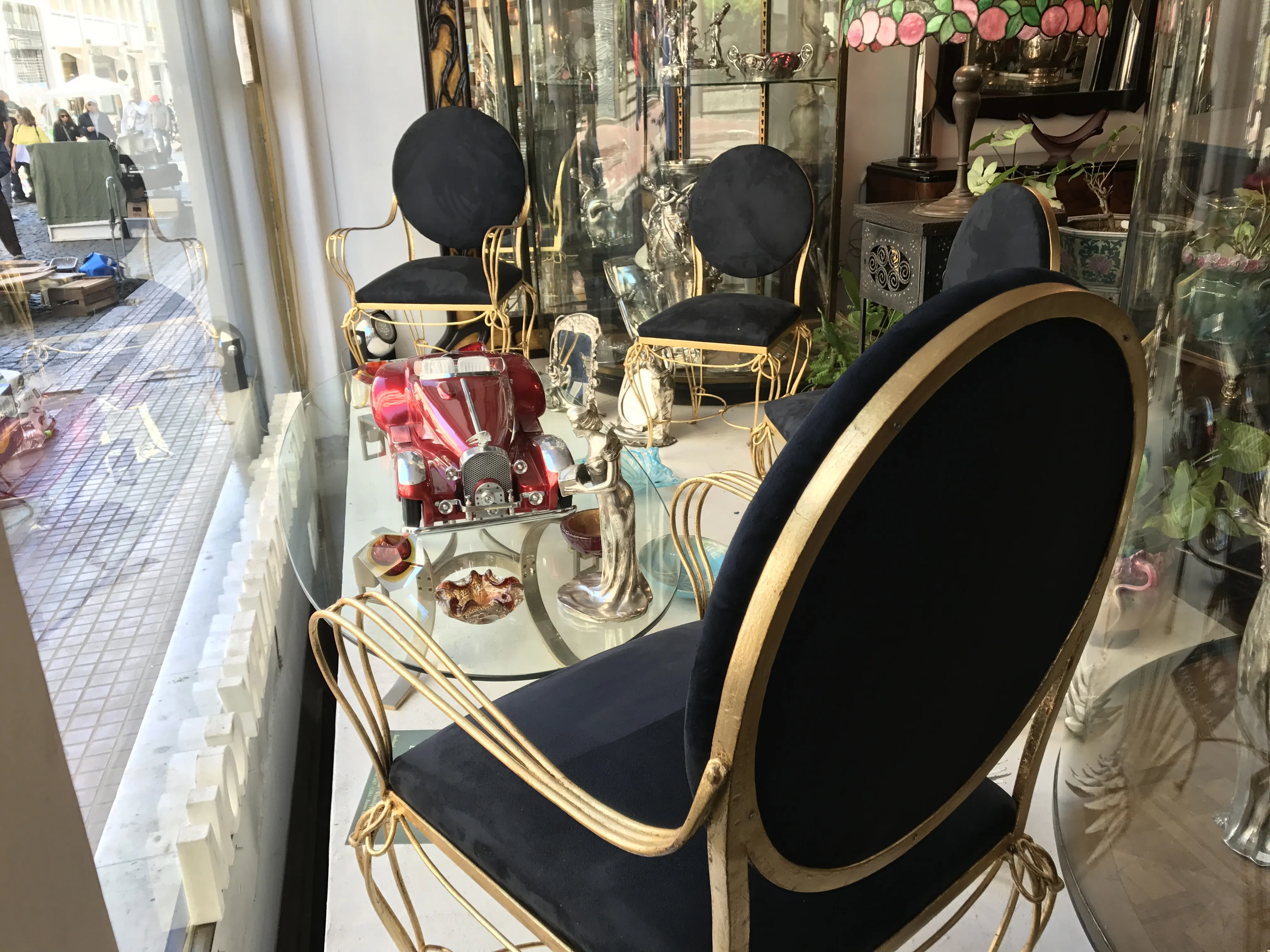 Mesa de jantar antiga para seis com cadeiras ornadas, detalhes decorativos ao fundo.