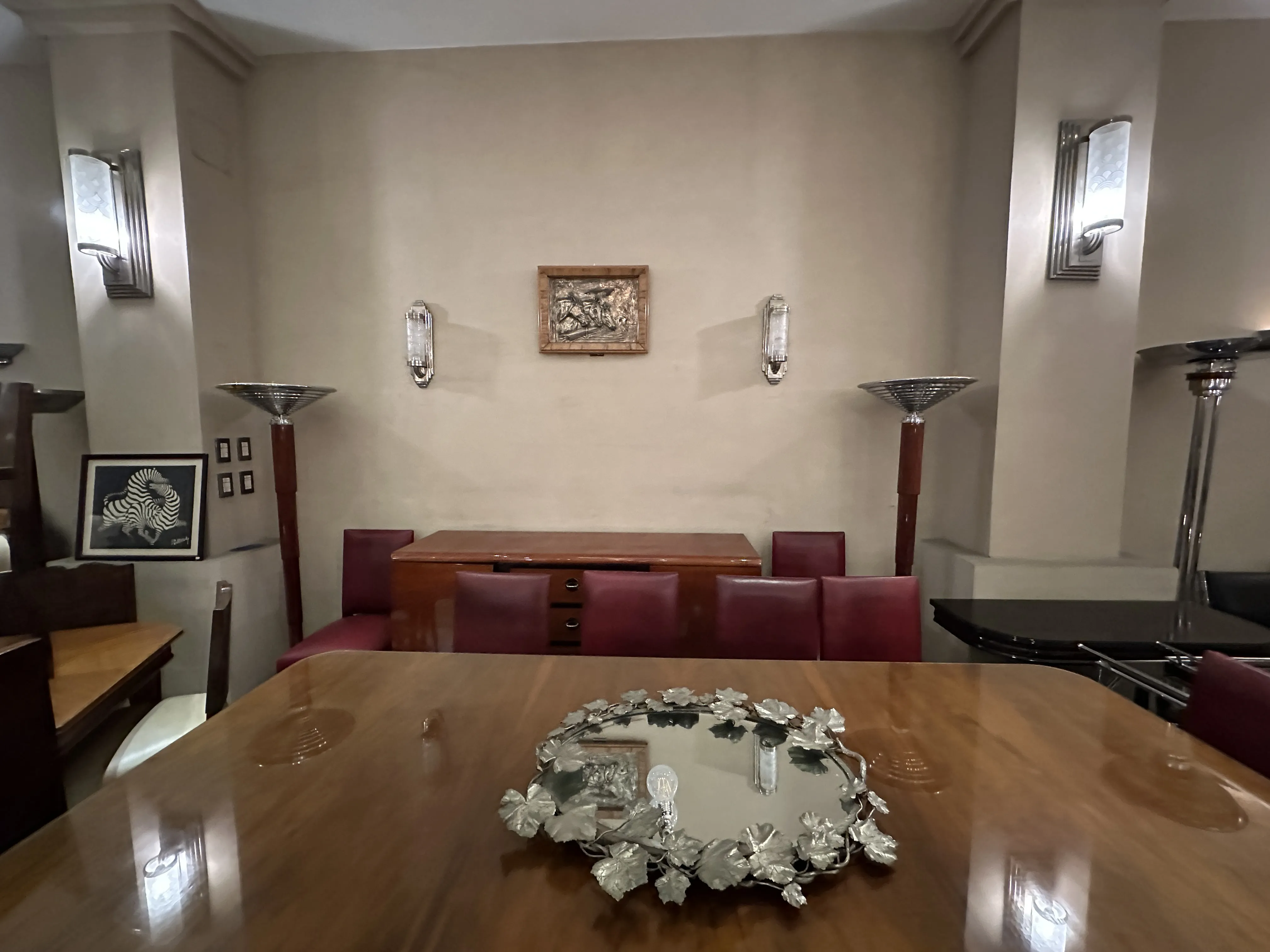 Table à manger antique Art Deco pour 10 personnes, entourée de chaises et de lampes élégantes.