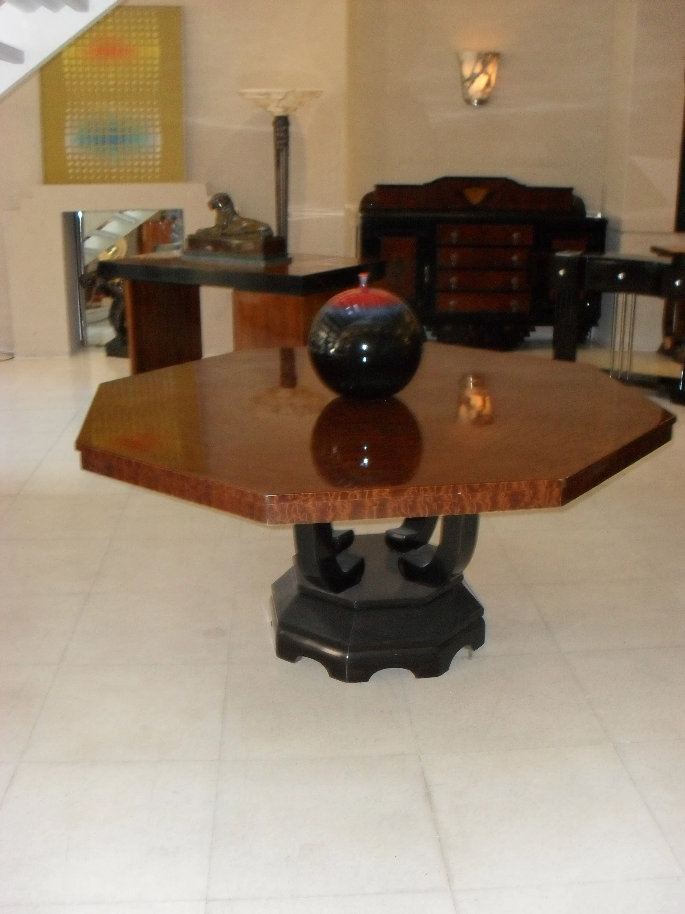 Octagonal dining table with black base and decorative sphere, elegant setting.