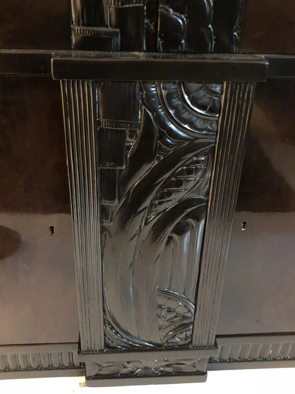 Detalle de una biblioteca antigua con diseños tallados a mano y un acabado brillante, en un entorno clásico.