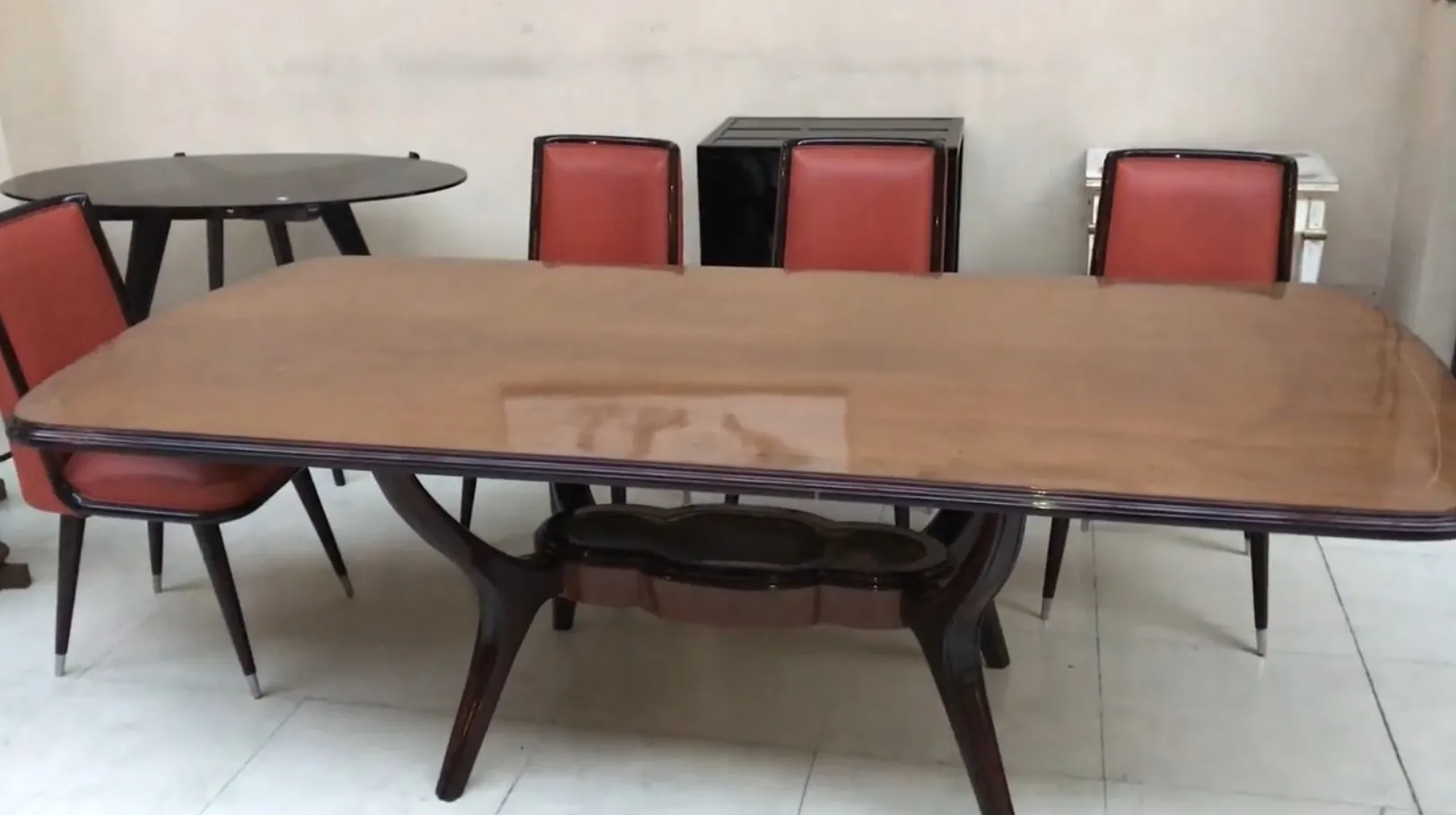 Mesa de comedor antigua de ocho personas con sillas rojas en un ambiente neutro