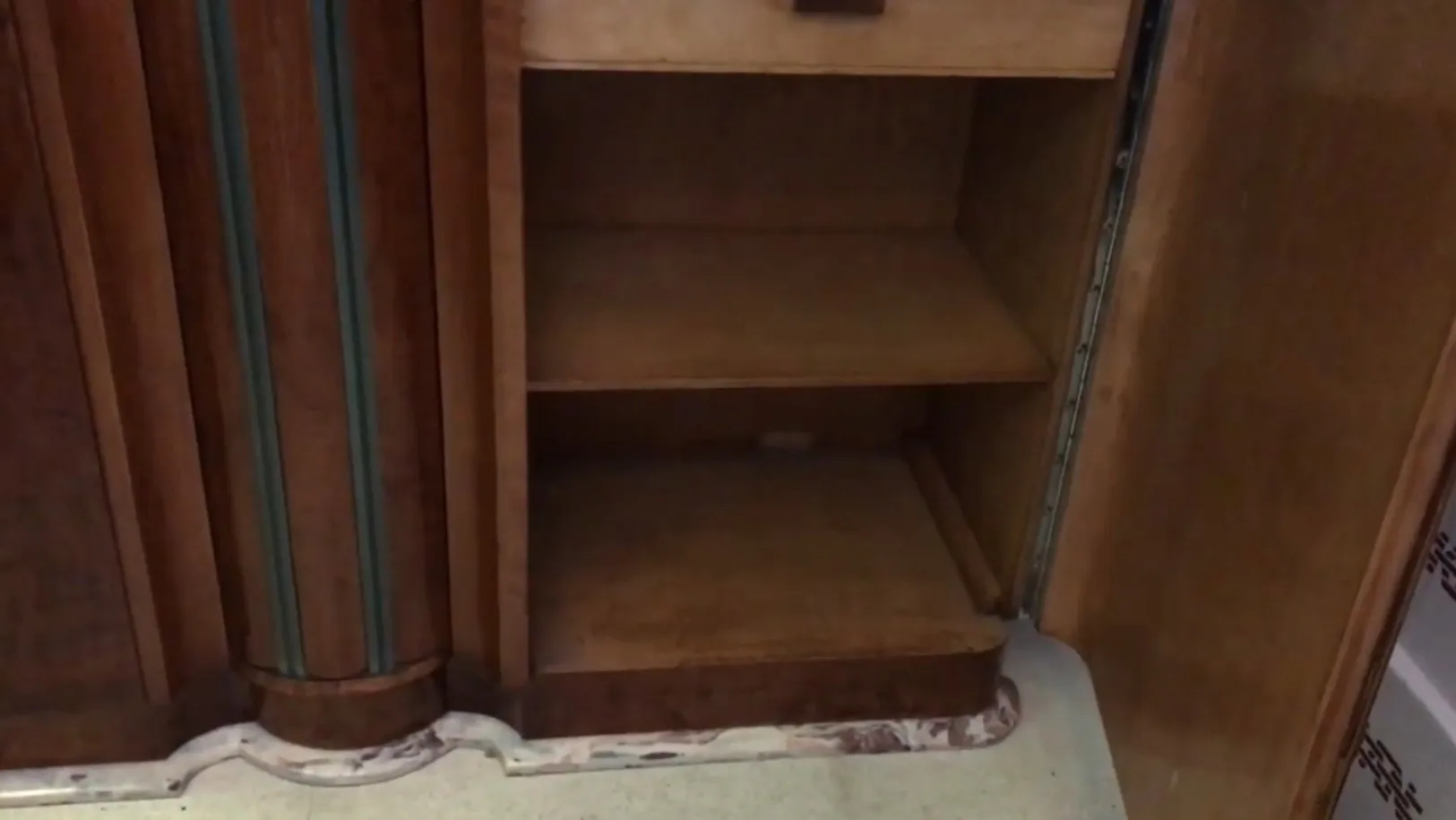 Visão interna de um estante de livros antigo com prateleiras vazias e detalhes elegantes.