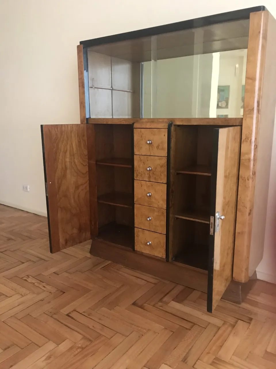 Antikes Bücherregal mit Spiegel, Schubladen und offenen Türen in einer minimalistischen Umgebung.