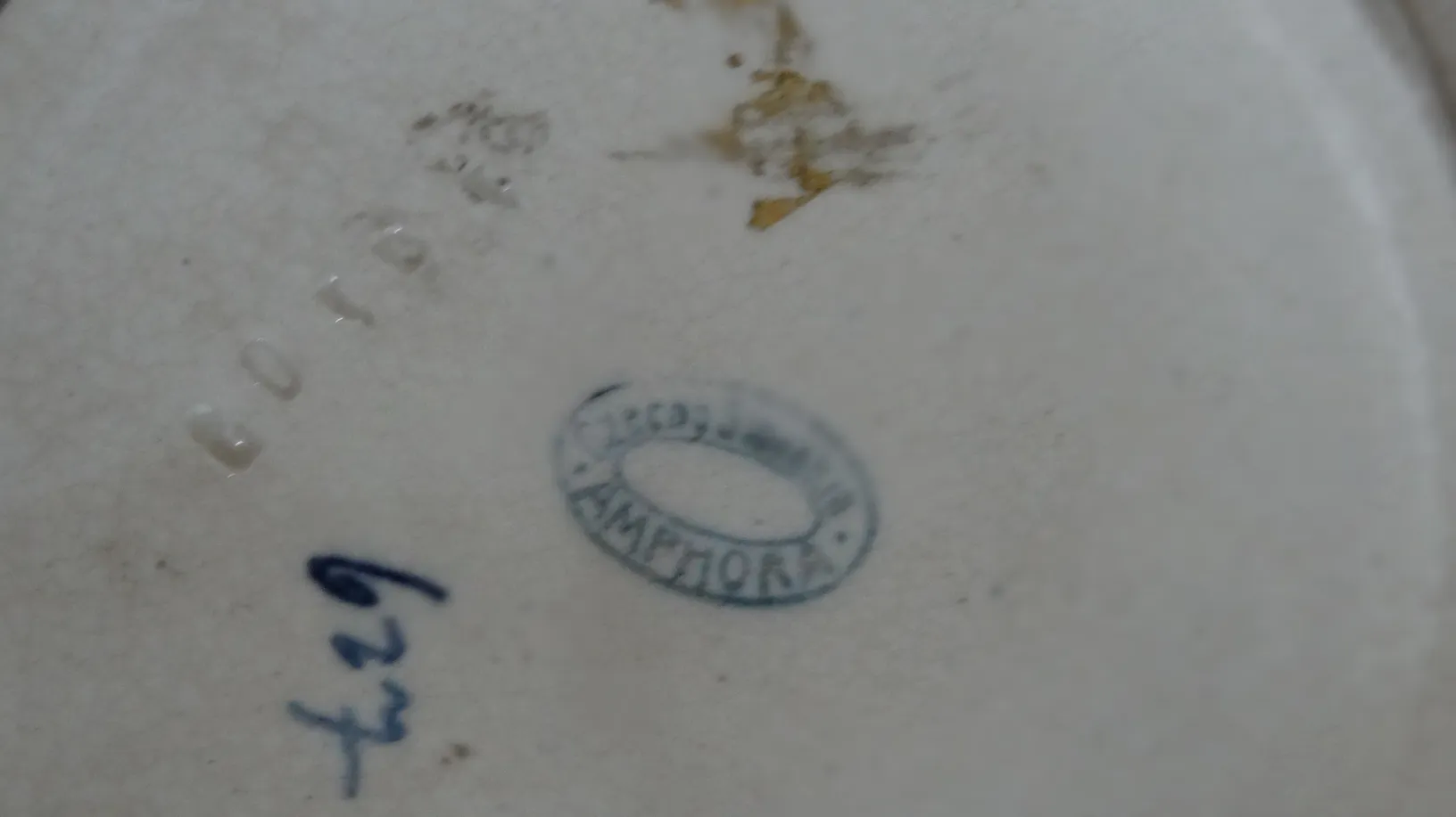 Unteransicht antiker Keramik mit sichtbarem Stempel, helle Details.