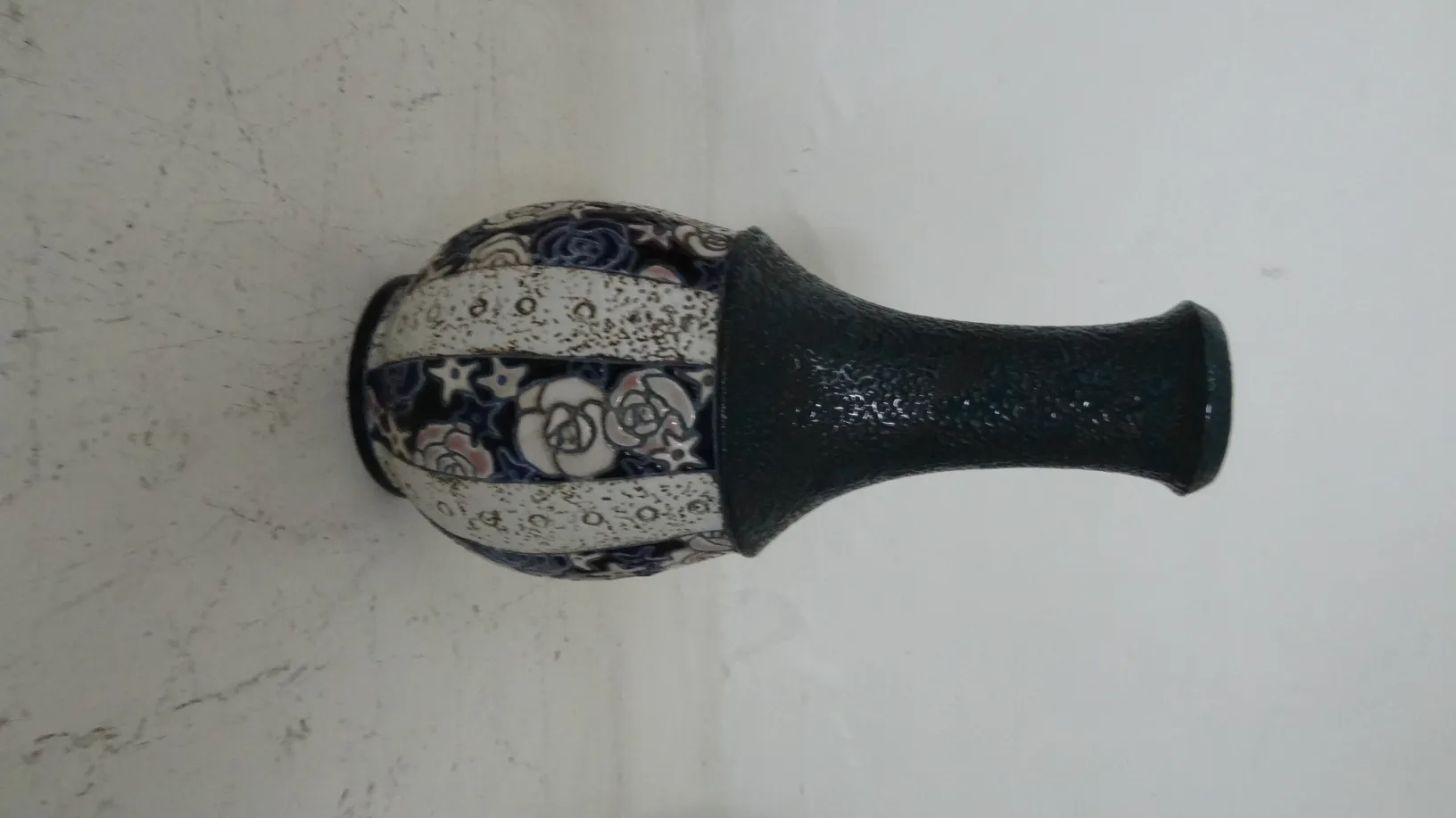 Céramique ancienne décorée de motifs floraux sur fond clair.