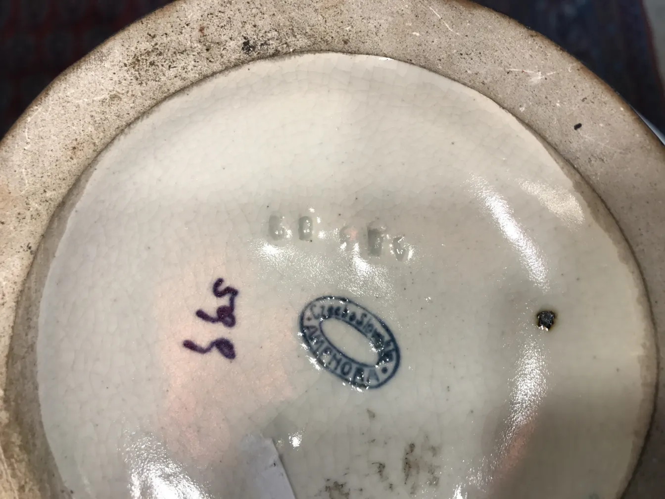 View of the bottom of an antique ceramic with distinctive marks and aged texture.