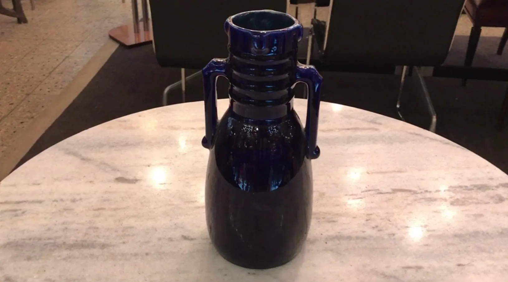 Blue ceramic jug with decorative handles on marble table
