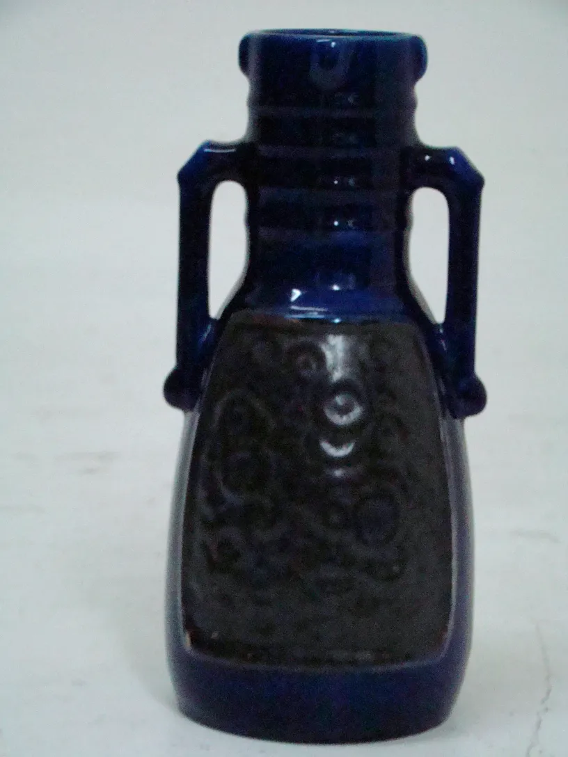 一件古董装饰陶瓷，具有蓝色和黑色细节，中性背景。