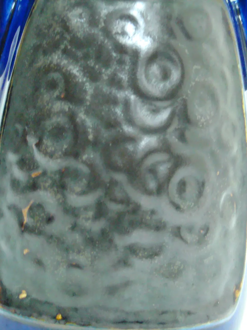 Antique ceramic decorated with spiral patterns and soft colors, detailed view.