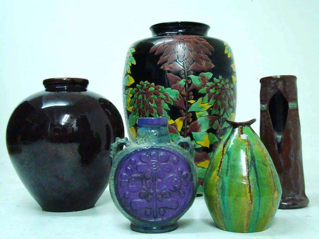 Vari pezzi di ceramica antica in diverse forme e colori su uno sfondo neutro.