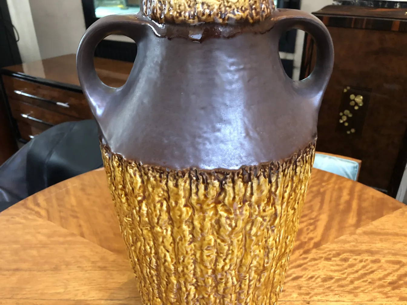 Cruche en céramique antique avec une finition texturée en tons de marron et d'or.