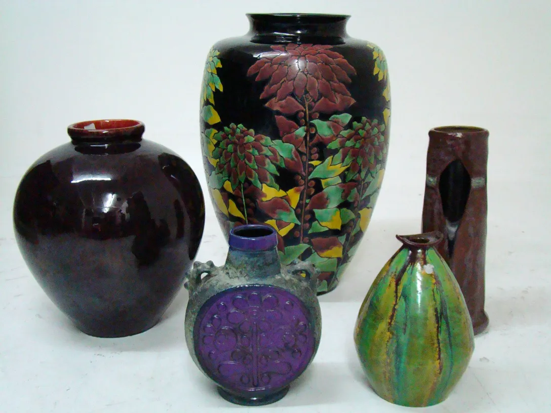 Vasos de cerâmica antiga de várias cores e formas em um ambiente neutro.