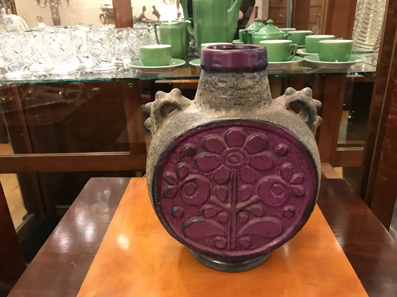 Antiga cerâmica com design floral vibrante, decorativa e única, cercada por cristaleiras.