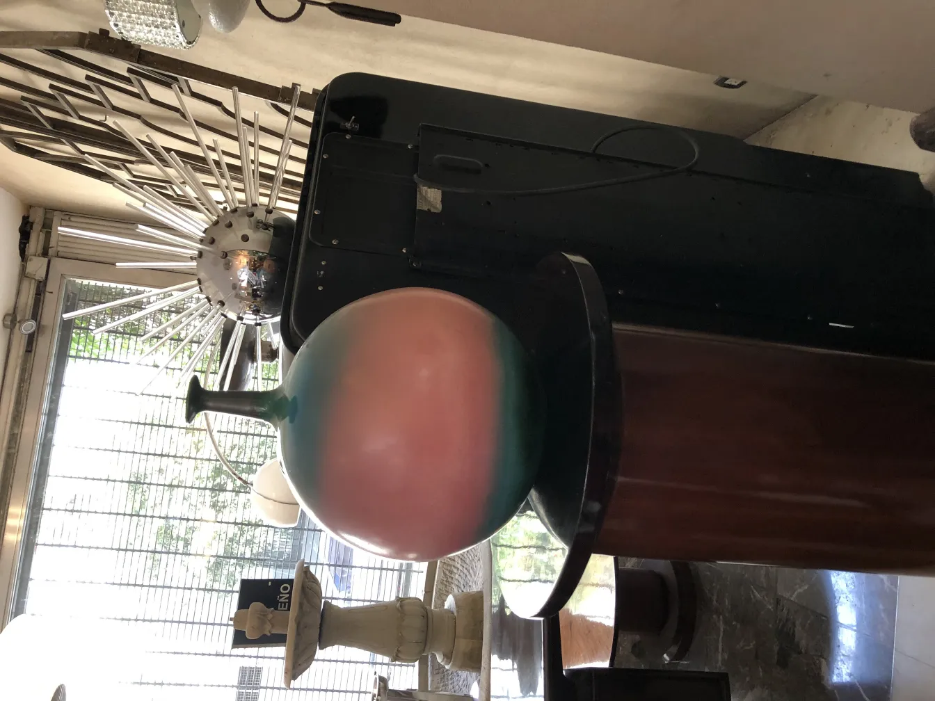 Sfera antica in ceramica colorata con finitura liscia, circondata da oggetti decorativi.