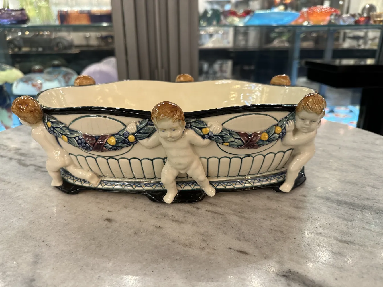 Antiga cerâmica com figuras infantis e decoração colorida.