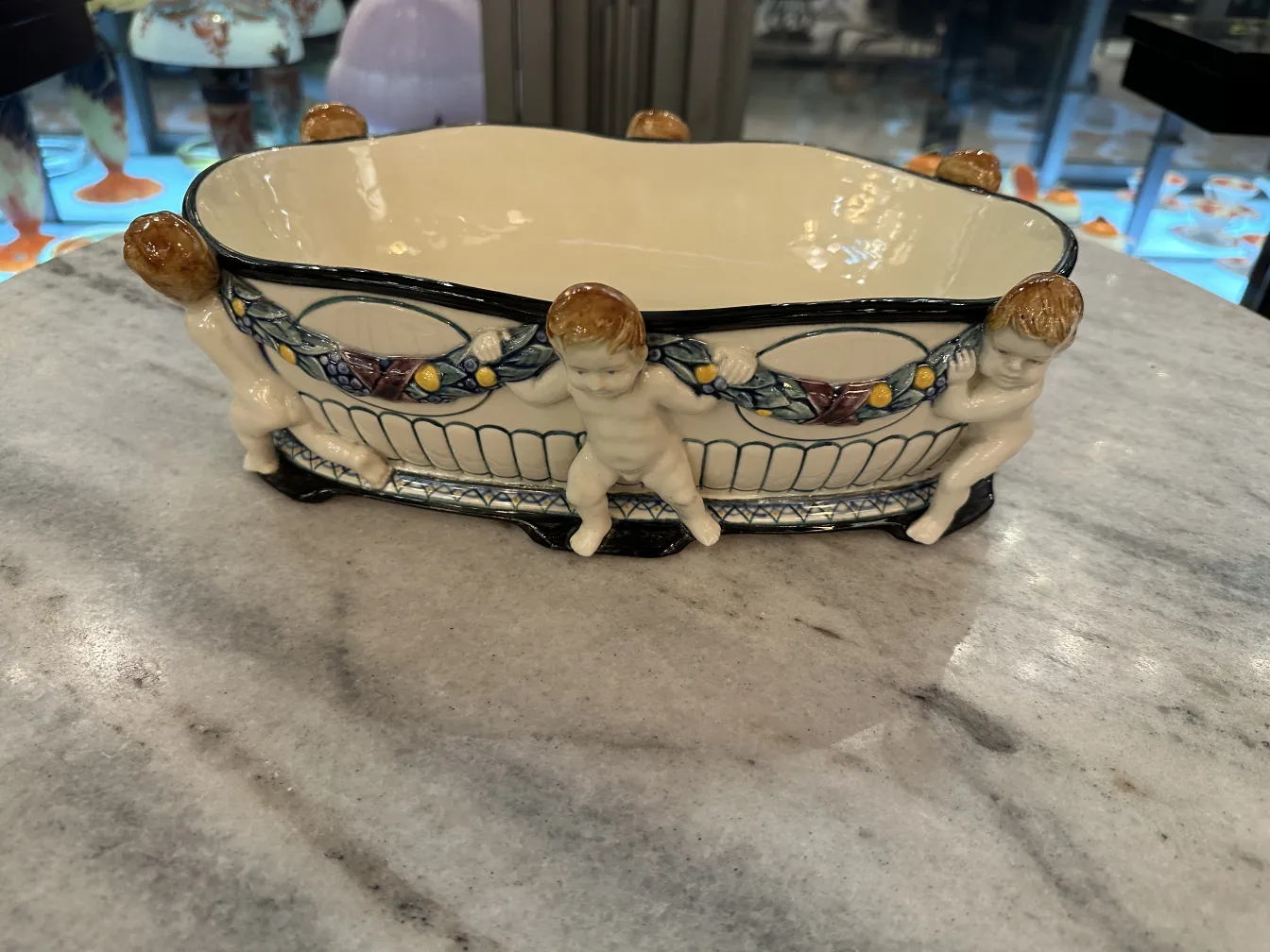 Antica ceramica con figure di cherubini ai lati.