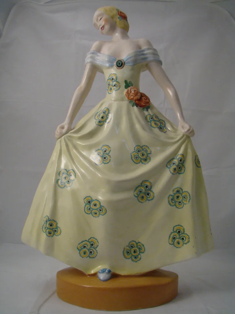 Figure ancienne en céramique Boch avec fleurs décoratives, robe jaune.