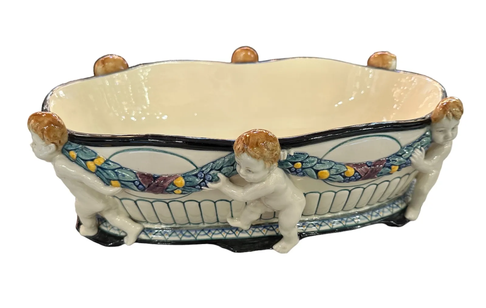 Antique ceramic featuring children figures holding a decoration. Decorative ambiance, soft colors