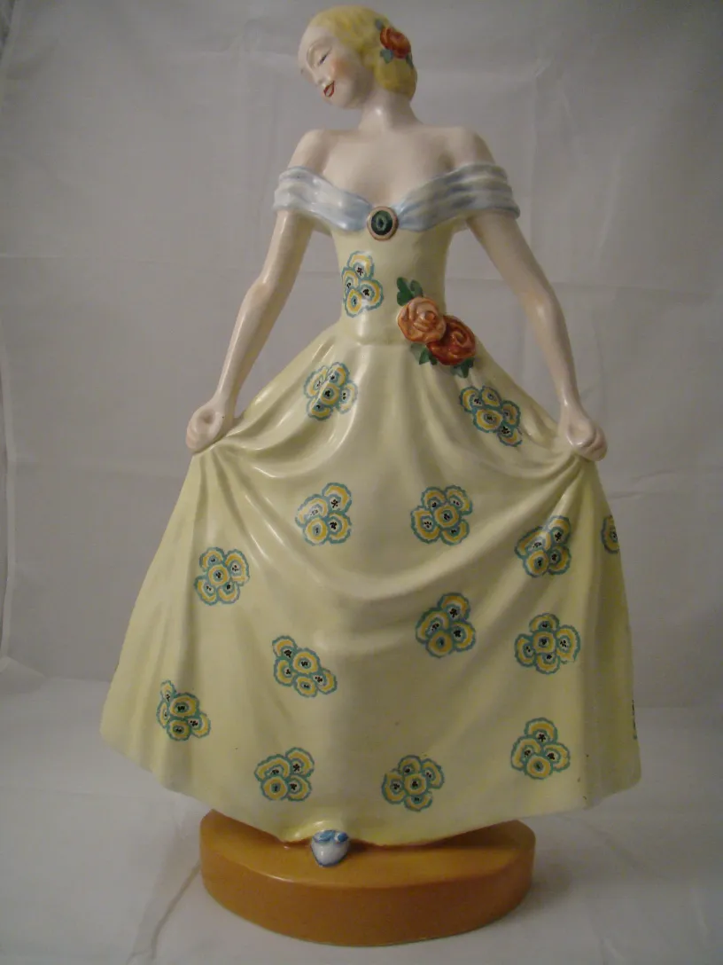 Un'antica statuetta di ceramica di una donna con un vestito giallo decorato con fiori