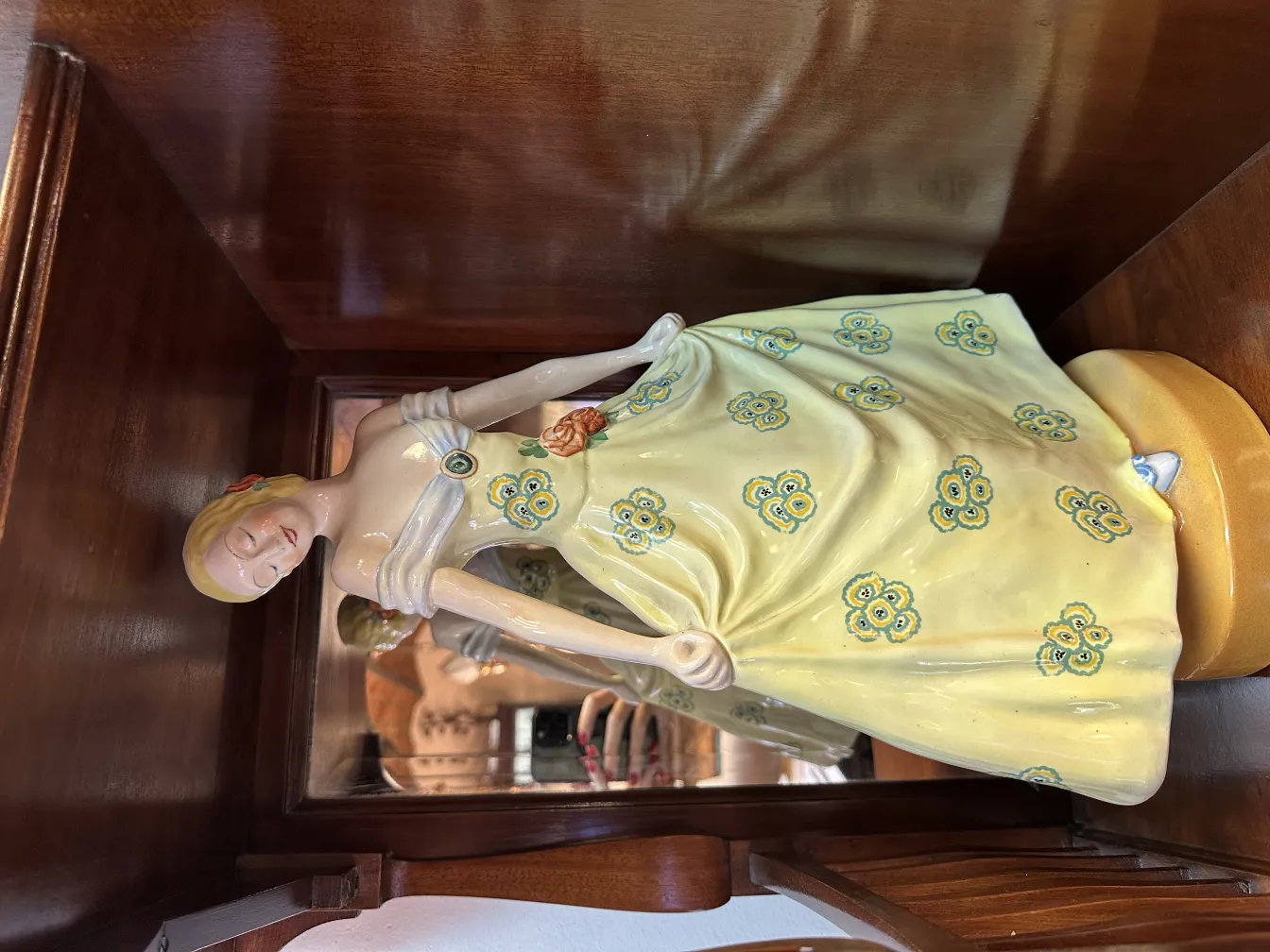 Figura antiga de cerâmica com vestido amarelo e flores