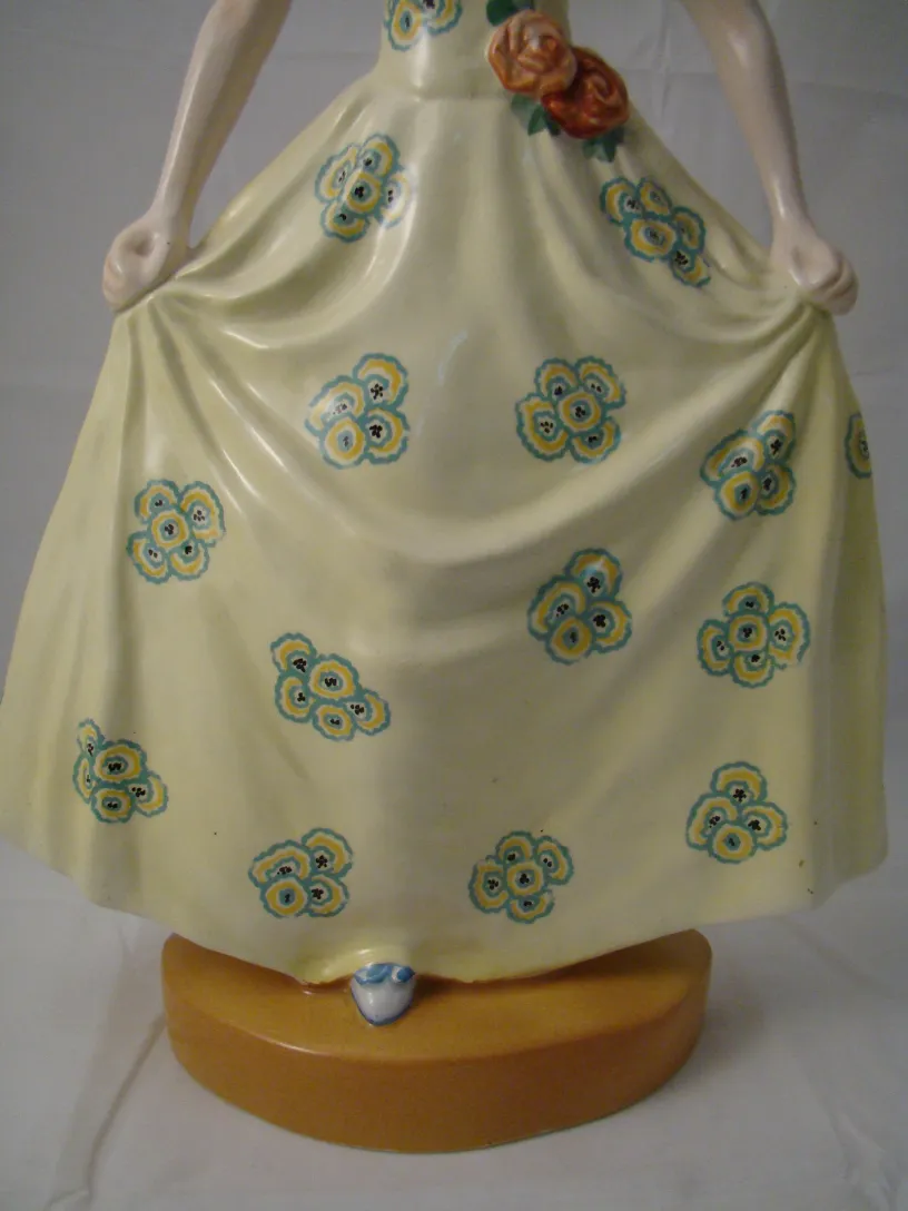 Antike Keramikfigur mit gelbem Kleid und Blumen