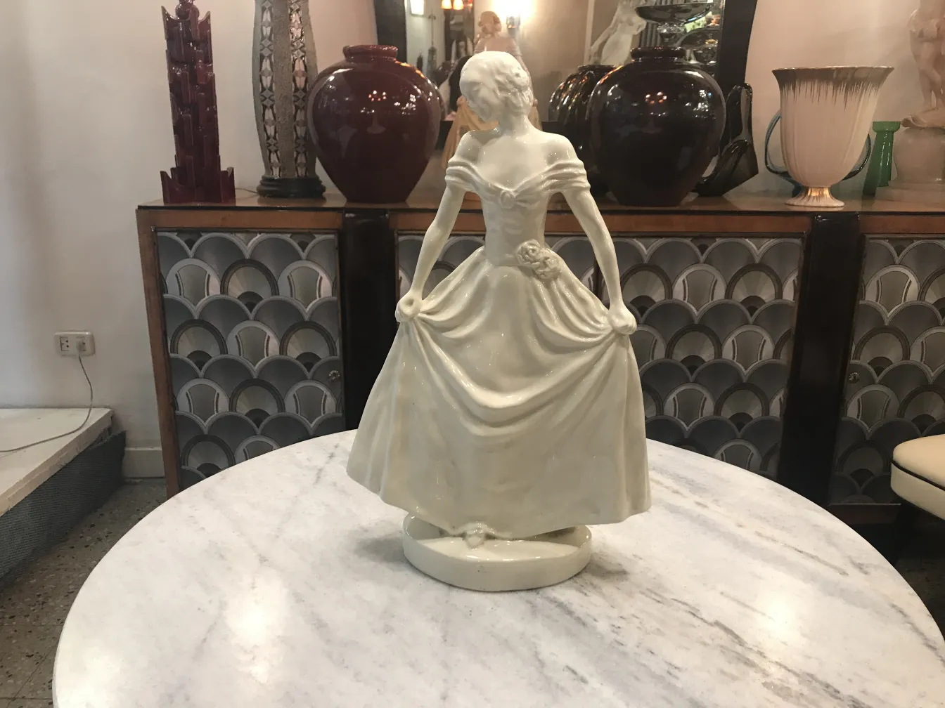 Figura decorativa de cerámica antigua en una mesa, con fondo de jarrones