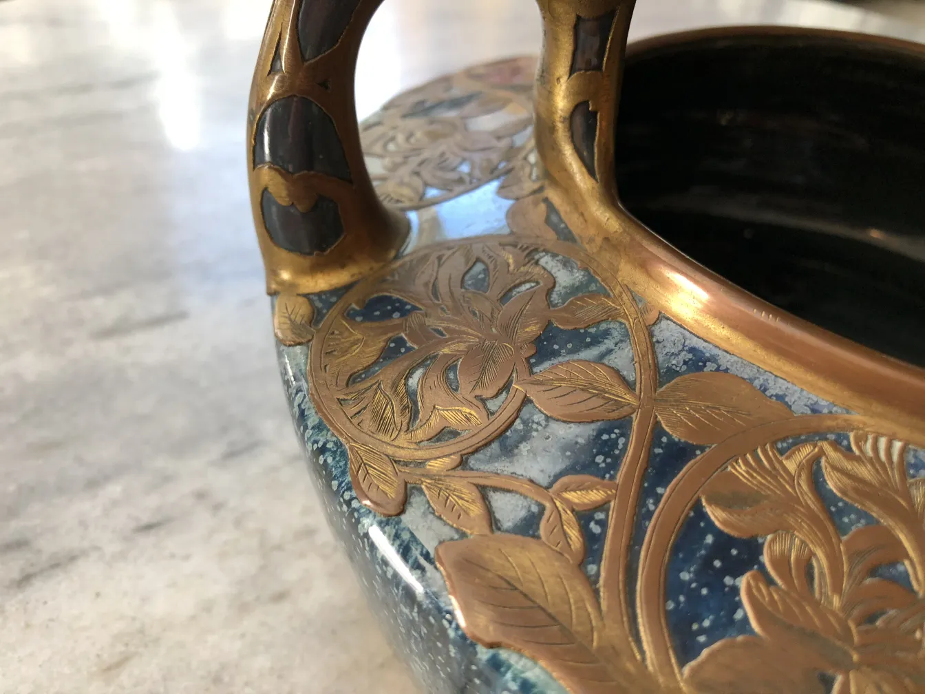 Cerâmica antiga decorativa com alças douradas e azuis.